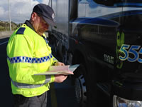 Photo of an officer checking truck documents by the road