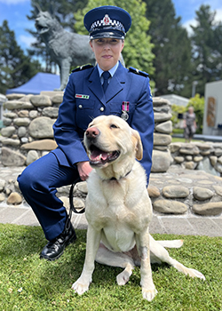  Senior Constable Zoe Eginton crouching down with detector dog Villa. 