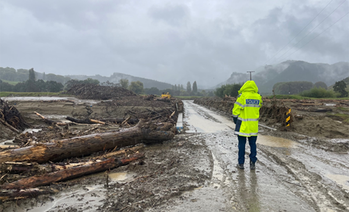 Sergeant Joll stands at the end of a railed bridge crossing the Mangaheia river in Tauwhareparae near Tologa Bay.