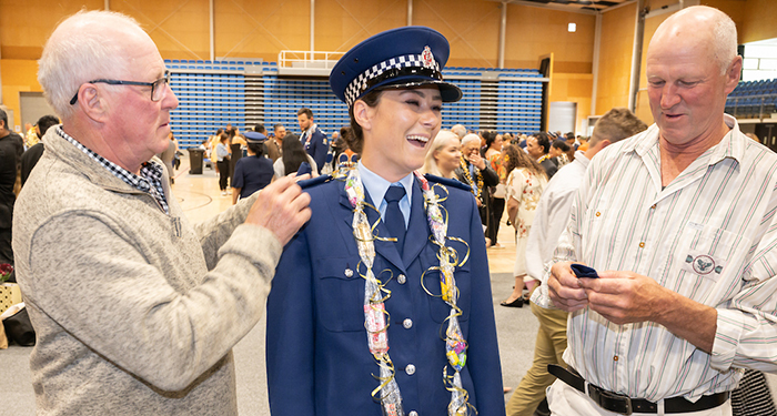 Former Customs Officer Tegan Harvey with her uncle Ross, left, and her dad Brett, right, fixing her new epaulettes on to her uniform.