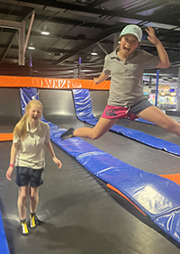 Two girls laughing while trampolining.