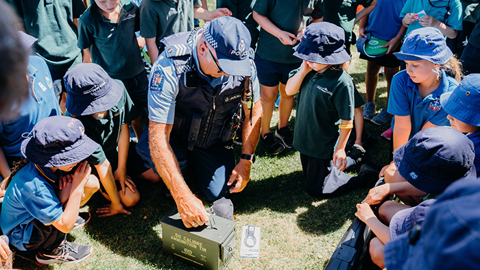 An officer surrounded by young students during a session on firearm safety.