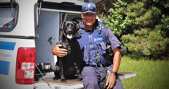 Patrick and Ripper pose for a photo sitting on the tailgate of a police dog van.