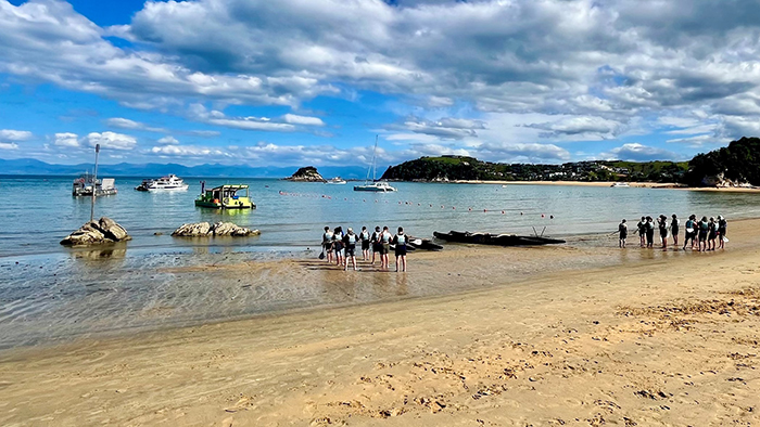 Teams walking to their waka on the beach.