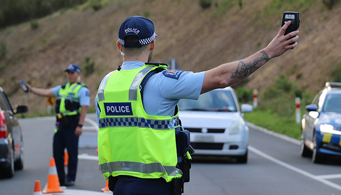 Officer signalling for a motorist to stop at a checkpoint. 