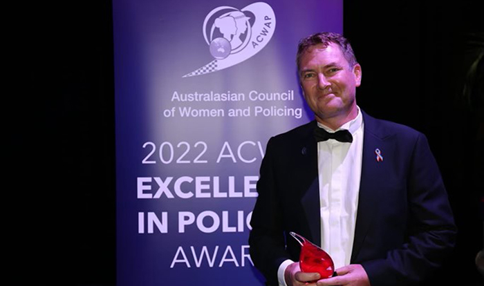 Assurance Director Mike Webb award in front of the 2022 ACWAP Excellence in Policing Awards.
