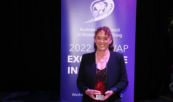 Senior Constable Chrissie Lunt holding her award in front of the 2022 ACWAP Excellence in Policing Awards.