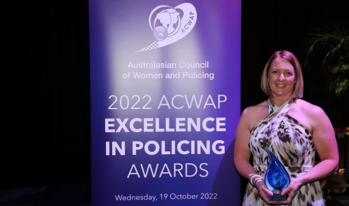 Senior Sergeant Yvette McKelvie holding her award in front of the 2022 ACWAP Excellence in Policing Awards