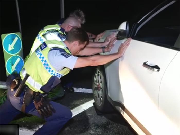 Police officers pushing the vehicle out of the way.