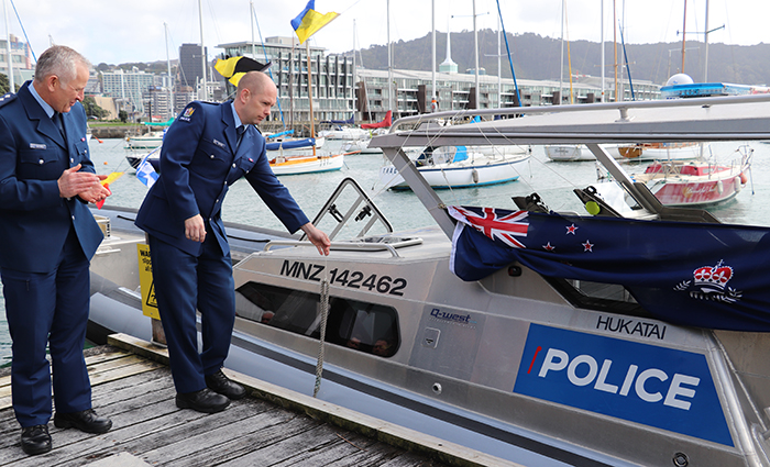 Ops Manager Inspector Nick Thom pulls back the New Zealand flag to reveal the name Hukatai on the side of the new rhib.