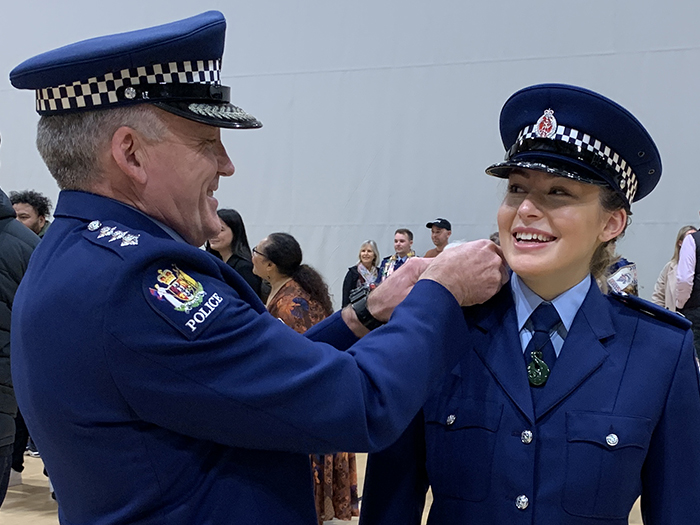 Mike Bowman helps Katie with her new epaulettes on graduation day.