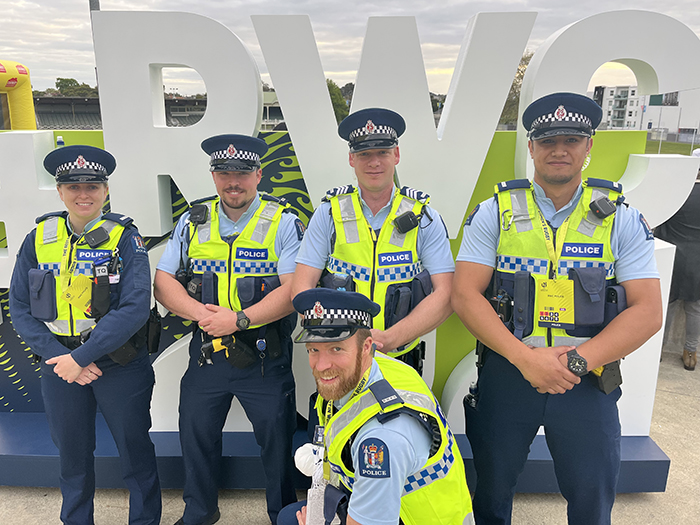 Group shot of officers in front of the RWC sign. Back row, from left: Constable Hannah Green, Constable Ryan Bush, Sergeant Laurent Schwarzenberger and Constable Eddie Aufai. Front row: Constable Adam Knock.