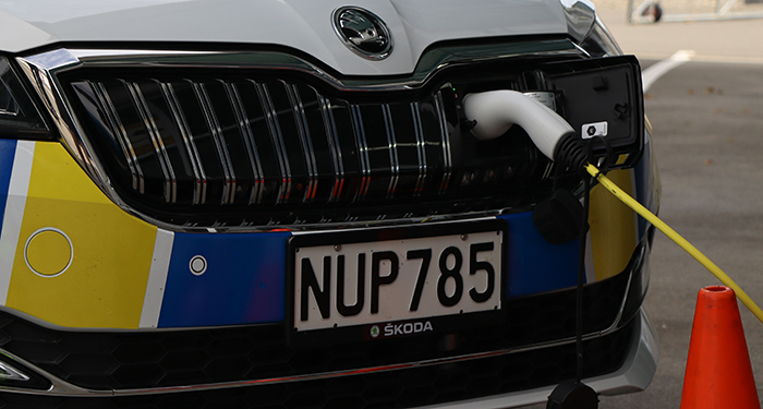 Close up on the front grill with the power cord connected to charge the vehicle.