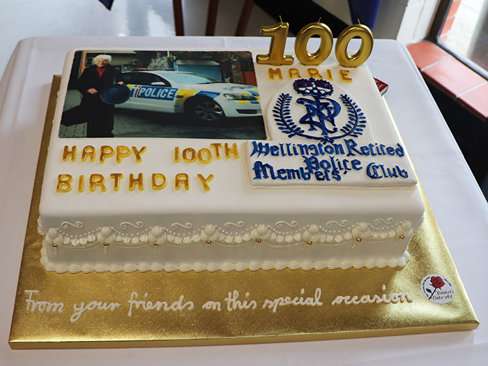 A birthday cake from the Wellington Retired Police Members' Club featuring a photo of Marie and the New Zealand Police crest.