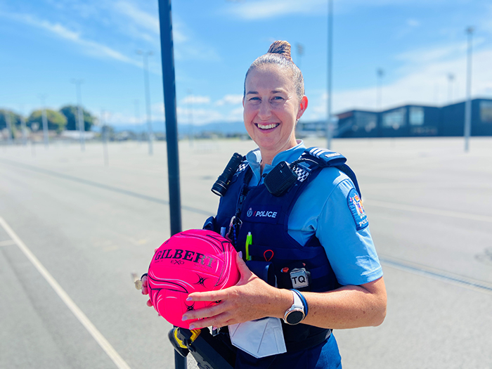 Sergeant Michelle Stagg in Police uniform holding a pink netball.