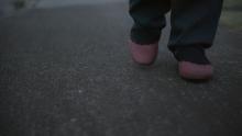 Reconstruction of Katrina in blue trackpants and wearing burgundy slip on shoes.