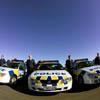 Police officers standing in a row by their patrol cars.