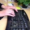 Hands typing at a keyboard on a desk.