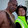 Māori male in traditional dress with Māori female in warden uniform.