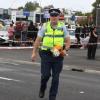 A Police officer takes flowers from the crowd to place at the scene