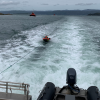 The Queen Elizabeth IV tows a recovered jetski behind it in the water. 