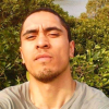 A young man looking at the camera with a slight goatee and furrowed brow