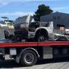 A broken-up vehicle is towed away.