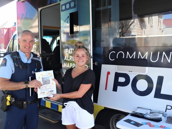 Alcohol Harm Reduction Sergeant Ian Paulin hands a student a Covid QR code for their flat