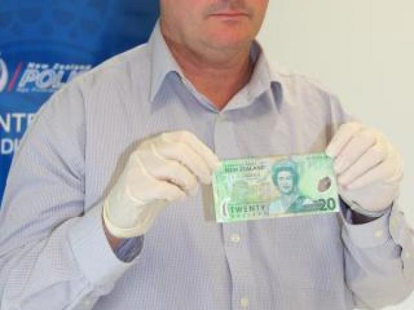 Acting Detective Sergeant Mike Freeman with one of the counterfeit notes.