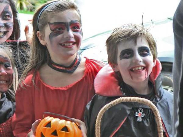 Four children in Halloween costumes at a door.