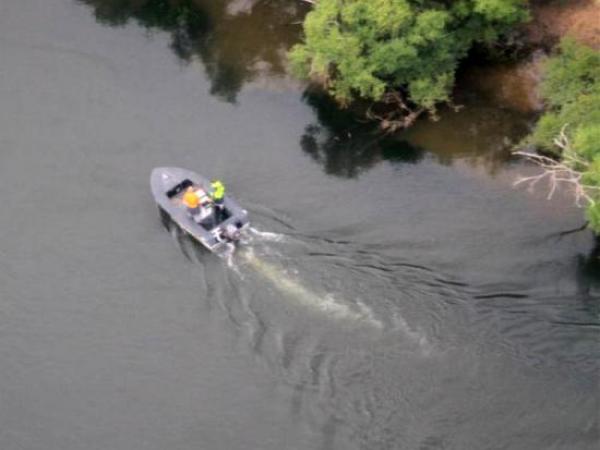 Rounding the corner: a Police helicopter flies over a search boat on the Waikato River