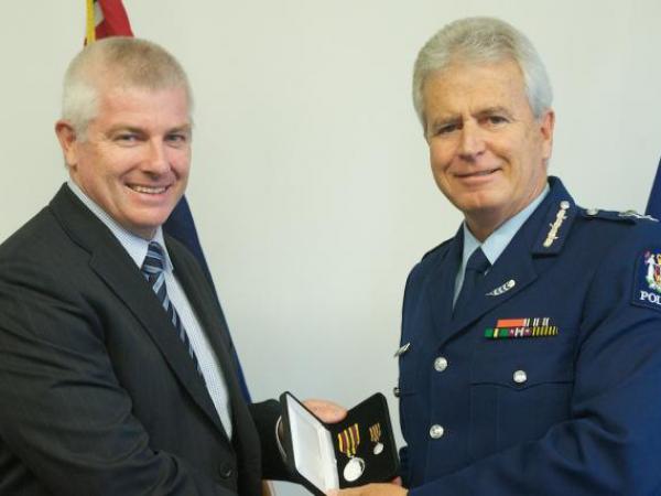 Commissioner Peter Marshall presents the Meritorious Service Medal to Detective Senior Sergeant Craig Hamilton