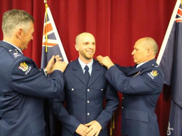Constable Braden Drew has his epaulettes swapped over by Commissioner Mike Bush and Detective Superintendent Rod Drew.