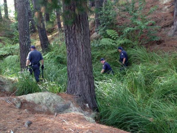 Police search a bush area close to the scene of Friday's fatal shooting
