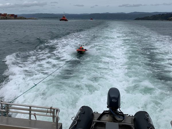 The Queen Elizabeth IV tows a recovered jetski behind it in the water. 