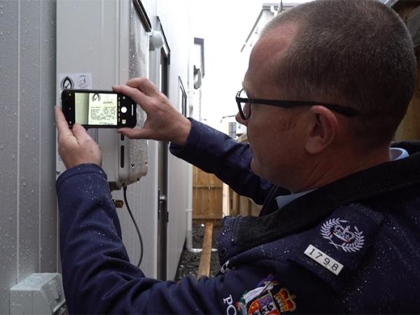 Acting Inspector Jonathon Chappel taking a photo of the serial number of a hot water system.