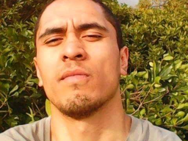 A young man looking at the camera with a slight goatee and furrowed brow