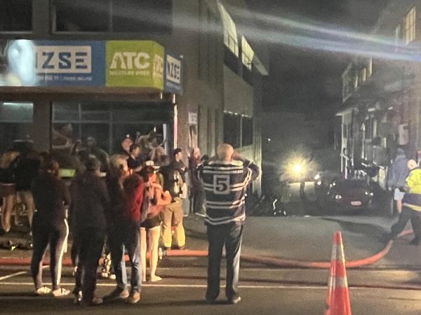 Tourists outside hostel as emergency services respond to fire.