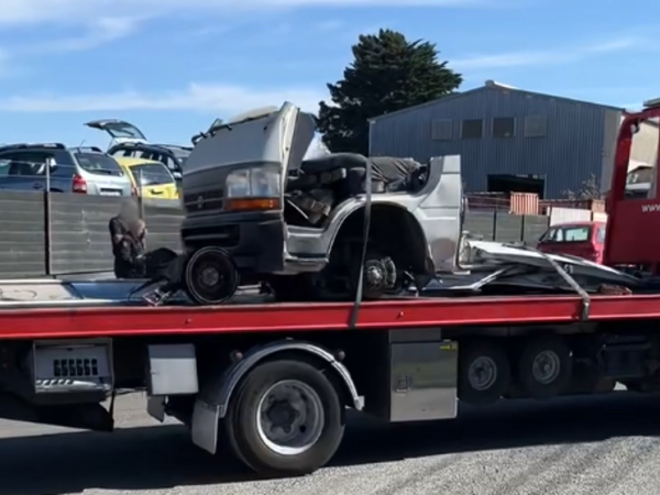 A broken-up vehicle is towed away.