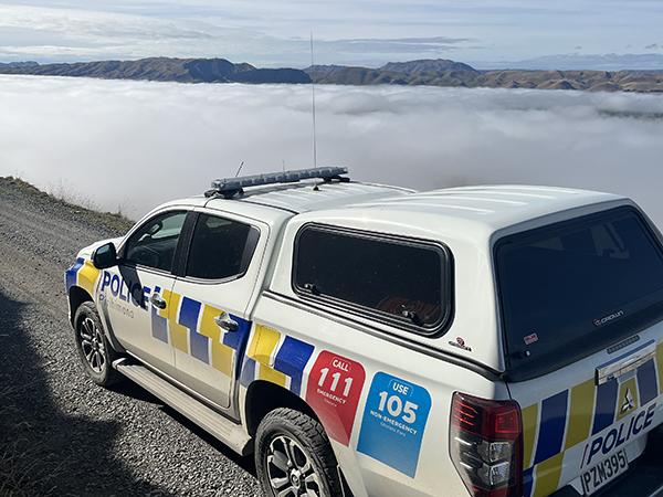 A police ute pictured on Burma road, Poukawa, in front of blue skies and low-level fog.