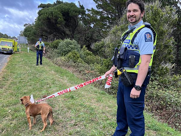Officer using crime scene tape as a lead to look after the puppy involved in the crash.