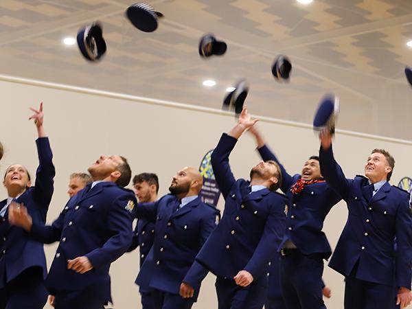 Wing 374 throwing their hats in the air after their graduation.