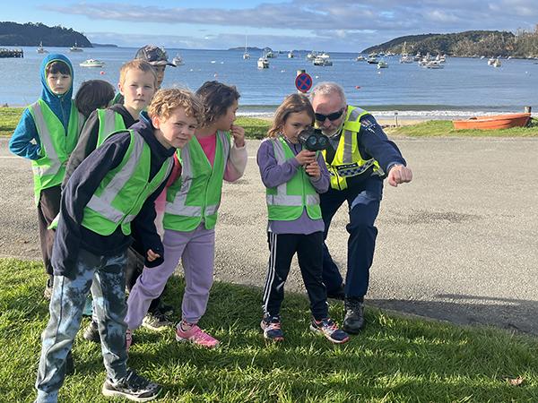 Police officer showing students how to measure vehicles' speed.