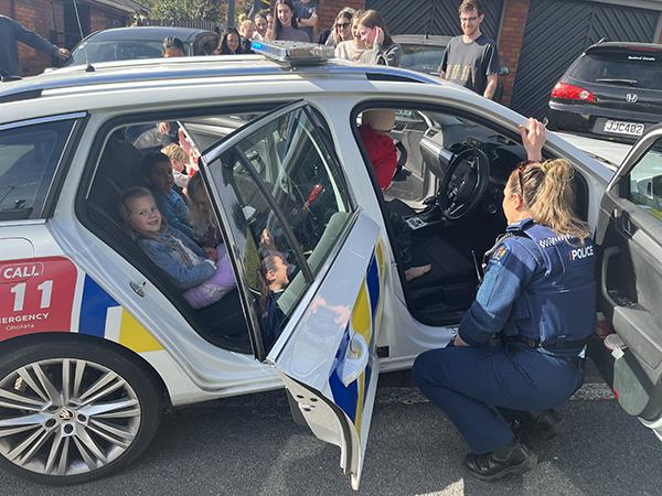 Officers showing Luca and his mates around their patrol car. 