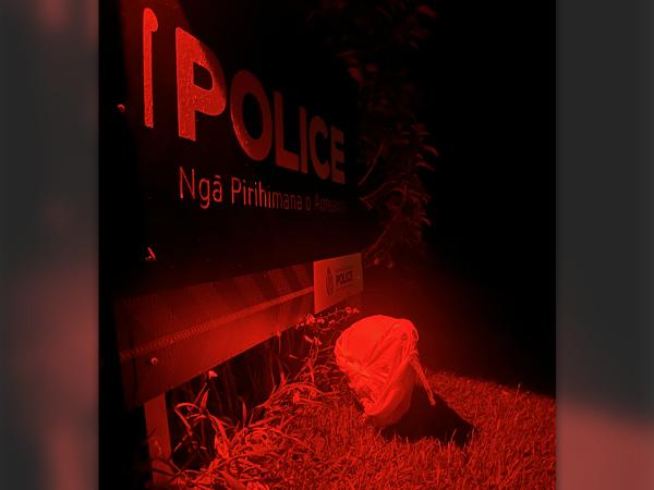 Red filter on a ghostly kiwi outside the Stewart Island Police Station sign.