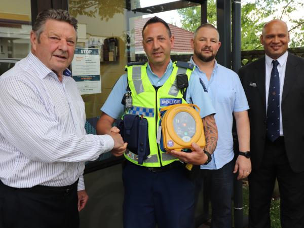 Whitianga Freemasons Master Elect John Smart presents the defibrillator to Constable Nick Preston, alongside Freemasons Marc Dre