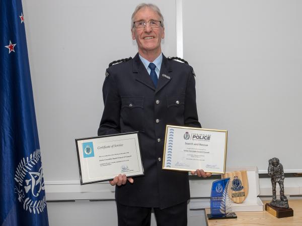 Dan O'Connell - in old-school uniform for his farewell - with his Police and SAR certificates of service and, on the table, a tr