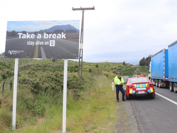 Constable Steven Knox beside one of the new 'Stay Alive on 5' signs.