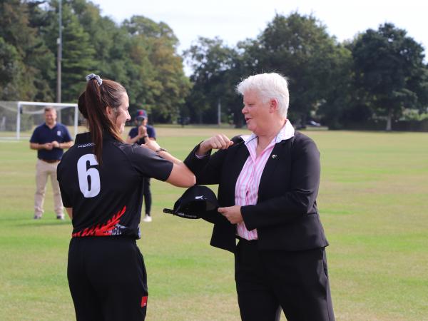 Observing COVID level 2 guidelines, former New Zealand Women's Captain Det Senior Sgt Sarah Illingworth presents a cap to former