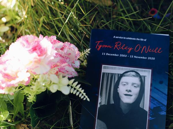 Flowers next to an order of service with Tyson's photo on the cover.